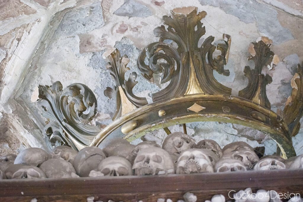 Carved gilded crown on top of a pile of skulls in one of the Sedlec Ossuary bone pyramids