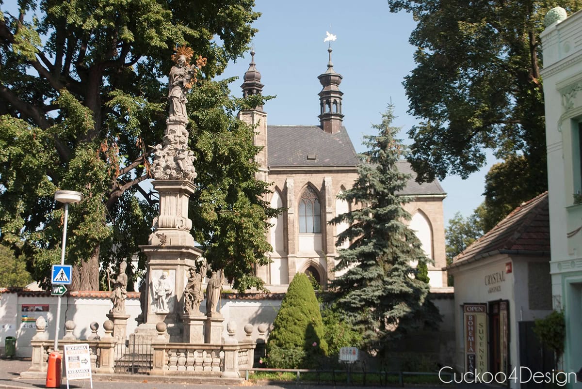 Church tower and stone column on the street near the Sedlec Ossuary in Kutná Hora